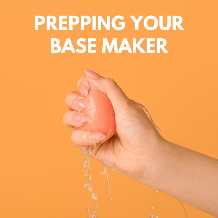 A hand squeezing out water from orange base maker sponge